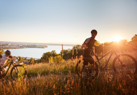 Två personer som cyklar uppför Huskvarnaberget i soldnedgång.